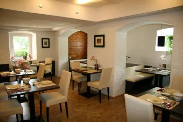 Ein modernes Restaurant mit hellen, minimalistischen Möbeln. Die Tische sind elegant gedeckt und schaffen eine einladende Atmosphäre.