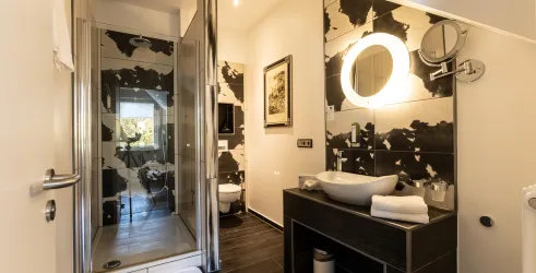 Ein modernes Badezimmer mit einer Duschkabine und stilvollen Wandfliesen. Der Waschbeckenbereich ist elegant und gut ausgestattet.