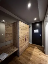 Ein moderner Flur mit Holzverkleidung und einem großen Schrank. Die Wände sind hell und die Beleuchtung ist angenehm.