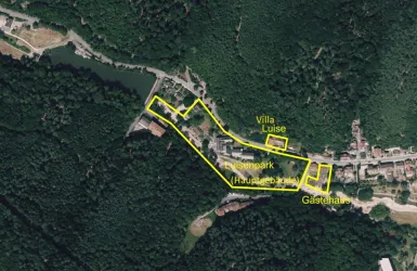Eine Übersichtskarte eines Geländes mit markierten Bereichen wie Villa Luise, einem Park und einem Gartenhaus. Die Umgebung ist von Wald und Wasser geprägt.