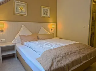 Ein gemütliches Schlafzimmer mit einem Doppelbett und hellen Wänden. Die Beleuchtung sorgt für eine entspannte Atmosphäre.