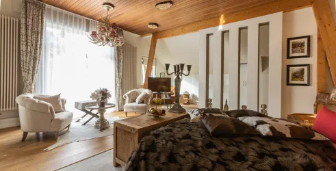 Ein stilvolles Schlafzimmer mit Holzdecken und einem gemütlichen Ambiente. Der Raum ist mit eleganten Möbeln und dekorativen Details ausgestattet.
