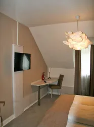 Ein modernes Schlafzimmer mit einem Flachbildfernseher und einem Schreibtisch. Die Wände sind in sanften Farben gehalten und es gibt eine stilvolle Lampe.