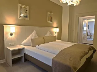 Ein gemütliches Schlafzimmer mit einem großen Bett und zwei Kissen. Die Wände sind neutral gestrichen und es gibt sanfte Beleuchtung.