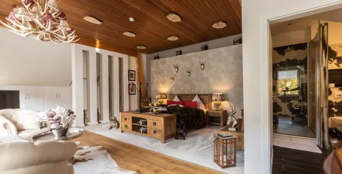 Ein stilvolles Schlafzimmer mit Holzdecke und eleganter Einrichtung. Strahlendes Licht und gemütliche Atmosphäre sorgen für einen einladenden Raum.