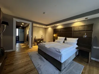 Ein modernes Schlafzimmer mit einem großen, bequemen Bett und warmen Holztönen. Die Beleuchtung schafft eine einladende Atmosphäre.