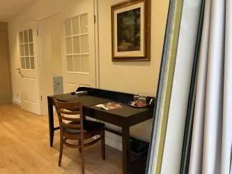 Ein stilvoll eingerichteter Raum mit einem Schreibtisch und einem Stuhl. An der Wand hängt ein Gemälde, und die Böden sind aus hellem Holz.