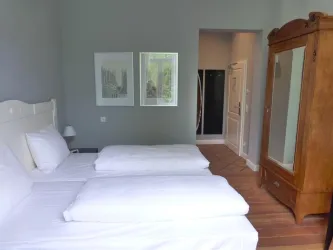 Ein gemütliches Schlafzimmer mit zwei Einzelbetten und einem schönen Holzschrank. An der Wand hängen zwei Bilder, und der Raum hat einen hellen, einladenden Look.