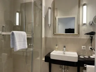 Ein modernes Badezimmer mit einer Glasdusche und einem eleganten Waschbecken. Die Wände sind hell und die Beleuchtung sorgt für ein freundliches Ambiente.