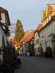 Eine ruhige Straße mit historischen Gebäuden und einem Blick auf die Berge. Die Atmosphäre ist beschaulich und einladend.