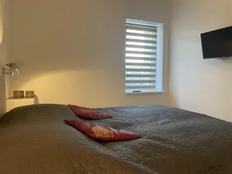 Das Schlafzimmer verfügt über einen Fernseher und ein Fenster zum ruhigen Innenhof.