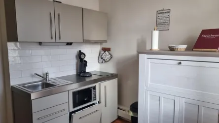 Eine moderne Küche mit hellen Schränken und Edelstahlgeräten.