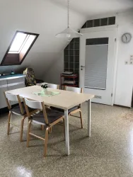 Ein helles Esszimmer mit einem Tisch und vier Stühlen. Die Wände sind in neutralen Farben, und ein Fenster sorgt für natürliches Licht.