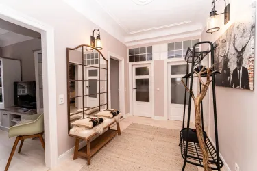 Stilvoller Eingangsbereich mit einem großen Spiegel und einer Garderobe, Regenschirm und Hausschuhe warten bereits auf neue Gäste.