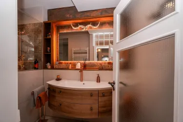 Ein Blick in den Spiegel....Ein modernes Badezimmer mit einem eleganten Holzwaschtisch und warmen Beleuchtungselementen.