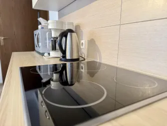 Eine moderne Küche mit einem glatten Kochfeld und einer elektrischen Wasserkocher. Im Hintergrund sind weitere Küchengeräte sichtbar.