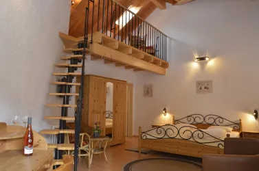 Ein gemütliches Zimmer mit Holzmöbeln und einer Treppe zu einer Galerie. Die Einrichtung ist modern und hell, ideal für einen entspannten Aufenthalt.