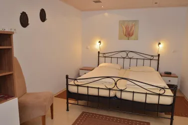 Das Bild zeigt ein gemütliches Schlafzimmer mit einem Doppelbett und weichen Bettdecken. Eine sanfte Beleuchtung und dezent dekorierte Wände sorgen für eine entspannte Atmosphäre.