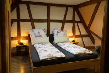 Ein gemütliches Schlafzimmer mit zwei Betten, dekoriert mit blühenden Kissen. Die Wände sind aus Holz und schaffen eine warme Atmosphäre.