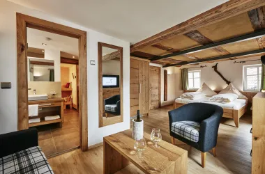Ein gemütliches Zimmer mit Holzdekor und modernen Annehmlichkeiten. Es gibt ein großes Bett, einen Wohnbereich und ein Badezimmer.
