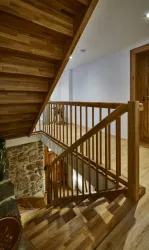Eine moderne Treppe aus Holz mit einem Geländer, das zu einem hellen Raum führt. Der Boden ist ebenfalls aus hellem Holz und erzeugt eine einladende Atmosphäre.