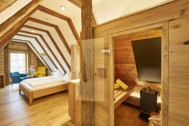 Ein gemütliches Zimmer mit Holzvertäfelung und einem modernen, hellen Design. Auf der linken Seite befindet sich ein Schlafzimmer und auf der rechten Seite eine Sauna.