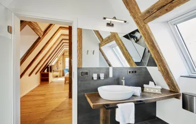 Ein stilvolles Badezimmer mit einem modernen Waschbecken und HolzDetails. Durch den offenen Zugang sieht man einen hellen und einladenden Wohnbereich.