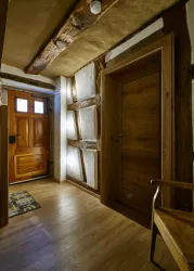 Ein gemütlicher Eingangsbereich mit Holzverkleidung und einer traditionellen Eingangstür. Der Raum hat einen warmen, einladenden Charakter.