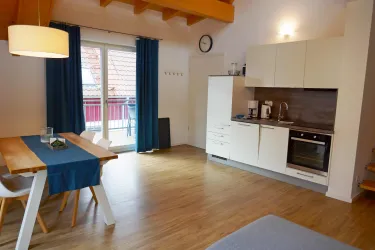 Eine helle und moderne Küche mit einem Esstisch und Stühlen. Große Fenster lassen viel Licht herein und bieten einen Blick nach draußen.