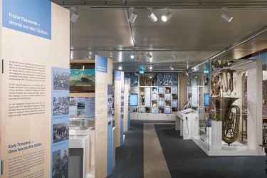 Ein Museum mit Ausstellungswänden und historischen Fotografien. Im Raum sind verschiedene Exponate und Informationsstände zu sehen.