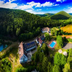 Eine malerische Berglandschaft mit einer schönen Unterkunft und einem Swimmingpool. Umgeben von üppigem Wald und grünen Wiesen.