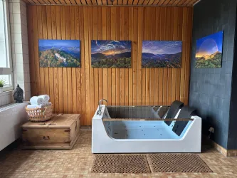 Ein moderner Raum mit einem Whirlpool und Holzverkleidung. An der Wand hängen Landschaftsbilder, die eine angenehme Atmosphäre schaffen.