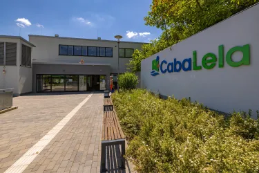 Ein modernes Gebäude mit einem einladenden Eingang. Das Logo von CabaLela ist gut sichtbar an der Wand angebracht.