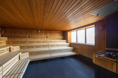 Ein entspannender Saal mit Holzbank und großen Fenstern. Der Raum ist hell und einladend gestaltet.