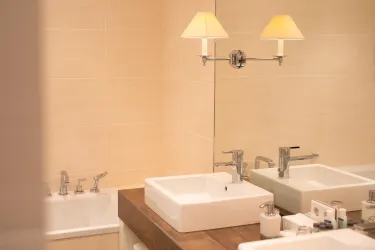 Ein modernes Badezimmer mit zwei Waschbecken und stilvollen Armaturen. Der Raum ist hell und freundlich, mit einer dezenten Beleuchtung.