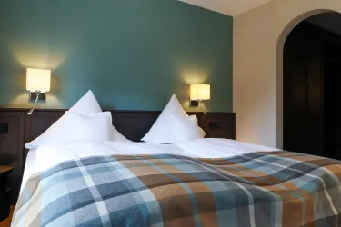Ein modernes Schlafzimmer mit zwei Betten und gemütlichen Kissen. Die Wände sind in verschiedenen Farben gestrichen und es gibt Nachttischlampen.