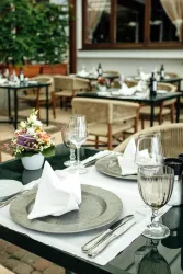 Ein elegantes Restaurant mit schön gedeckten Tischen im Freien. Die Tische sind mit Gläsern und frischen Blumen dekoriert.