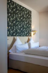 Ein gemütliches Schlafzimmer mit zwei Kissen und einer attraktiven Blumen-Tapete. Die warmen Farben schaffen eine einladende Atmosphäre.