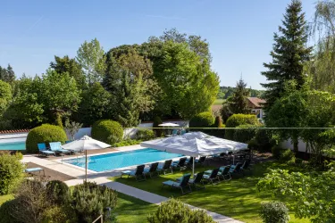 Ein schöner Garten mit einem Schwimmbad und bequemen Liegen. Die Umgebung ist grün und einladend, ideal zum Entspannen.