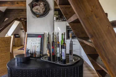 Ein stilvoller Tisch mit einer Auswahl an Flaschen und einem dekorativen Schild. Im Hintergrund sind Holzbalken und eine gemütliche Wohnatmosphäre sichtbar.