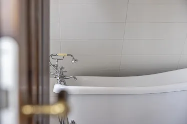 Eine moderne Badewanne mit glänzenden Armaturen in einem hellen Raum. Die Wände sind schlicht und hell gefliest.