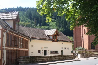 Die Alte Samenklenge versehen mit einem schrägen Dach und Holzfassade. Im Hintergrund sind Bäume zu sehen.