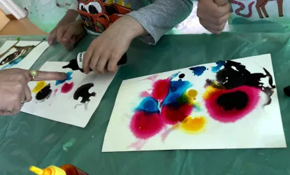 Kinder malen mit bunten Farben auf Papier. Die Bilder zeigen lebendige Farbflecken in verschiedenen Formen.