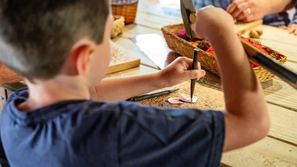 Junge arbeitet mit Hammer und Meisel