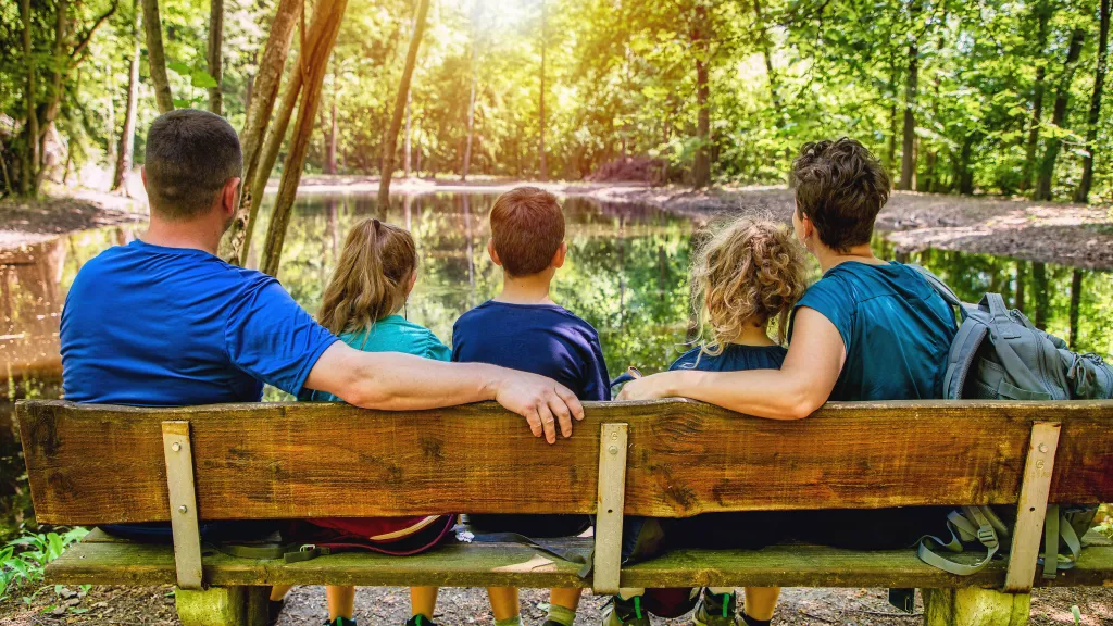 Familie sitzt auf einer Bank und wird von hinten abgebildet