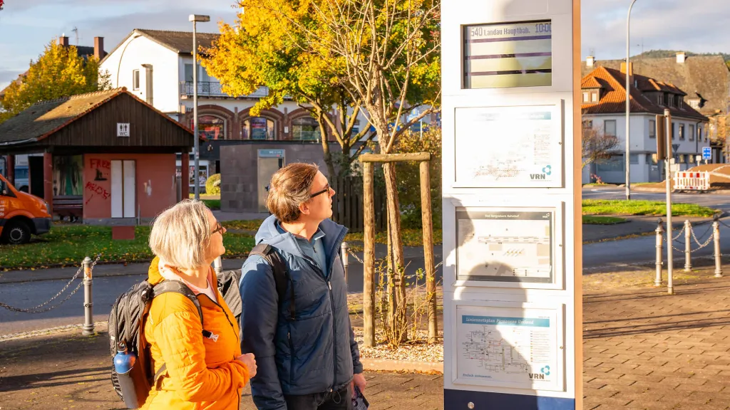 Ein Pärchen schaut auf die Fahrplaninformation