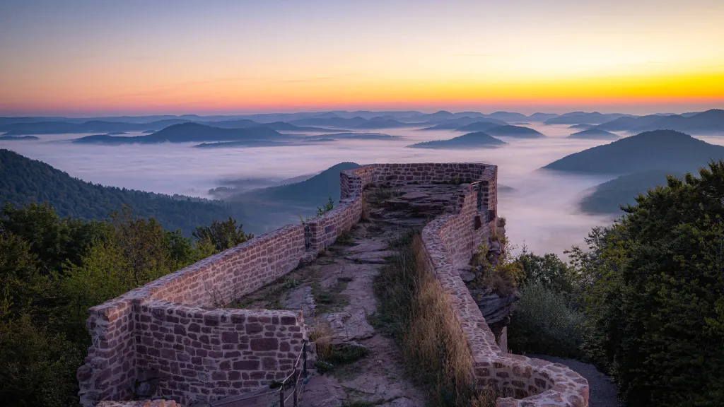 Blick über die Burgruine beim Sonnenaufgang in den nebelbedeckten Pfälzerwald