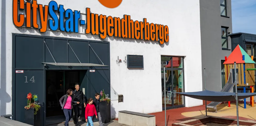 Familie kommt aus Jugendherberge ruasgelaufen