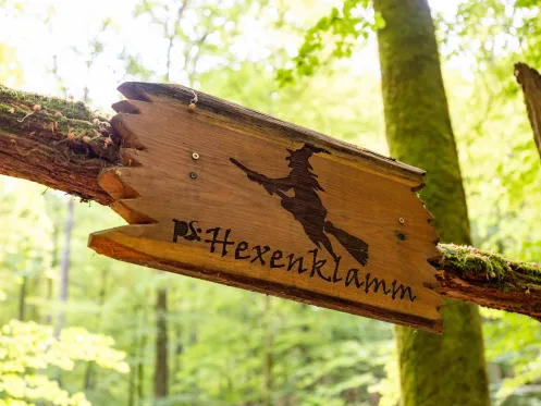 Holzschild mit der Aufschrift Hexenklamm und einer Hexe auf einem Besen