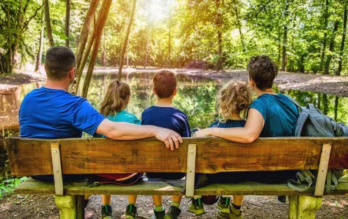 Familie sitzt auf einer Bank und wird von hinten abgebildet